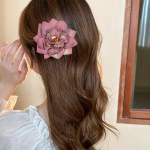 Close-up detail of a vintage dusty rose flower duckbill hair clip, elegant side accessory.