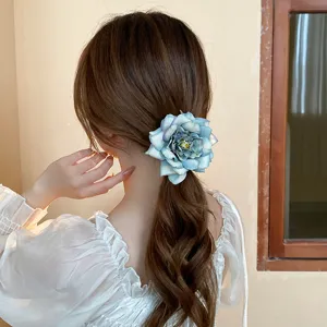 Exquisite blue rose hair clip detail showing the multi-layered fabric petals and vintage design.