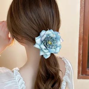 Close-up detail of the elegant blue rose fabric hair clip, featuring a secure duckbill design.