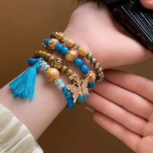Bohemian multi-layer wooden bead bracelet set with turquoise stones and gold butterfly pendant.