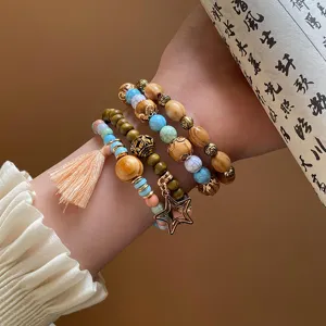 Boho multi-layer wooden bead bracelet detail close-up with tassel and star pendant.