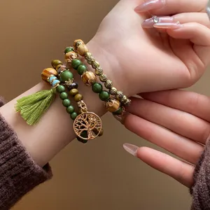 Bohemian multi-layer wooden bead bracelet with tree of life pendant and green tassel detail.