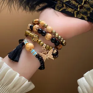 Bohemian multi-layer wooden bead bracelet detail, featuring metal charms, tassels and butterfly.