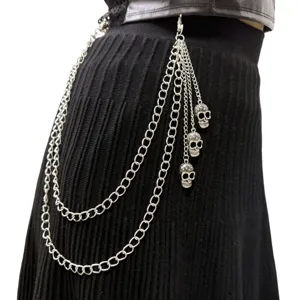 Close-up of multi-layer punk metal waist chain with skull pendants on black skirt.