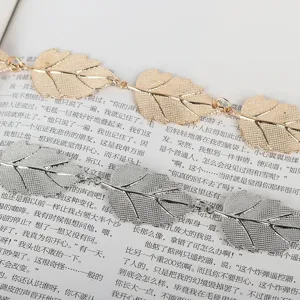 Gros plan d'une chaîne de corps élégante à feuilles métalliques dorées et argentées.