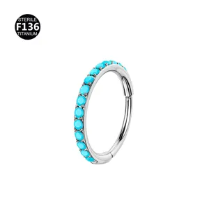 Detailed view of titanium hinged segment piercing ring with vibrant turquoise stones for body art.