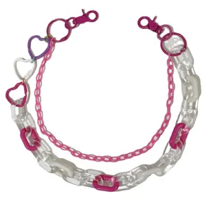Acrylic chain detail with pink hearts, clear links, rave streetwear pants accessory close up.