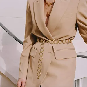 Detailed shot of a stylish gold metal interlocking ring waist chain worn on a blazer.