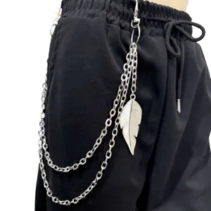 Close-up van meerlaagse metalen broekketting met bladhanger op zwarte streetwear broek.