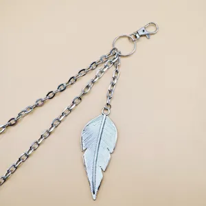 Close-up detail van zilveren metalen meerlaagse ketting met bladhanger en karabijnhaak.
