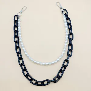 Détail raffiné de perles synthétiques et chaîne acrylique noire avec fermoirs métalliques.