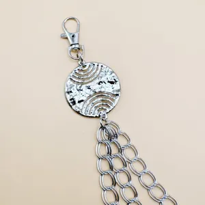 Silver metal punk pants chain detail showcasing textured round pendant and multi-layer chains.