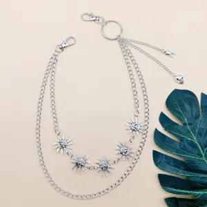 Detailed view of punk style silver metal multi-layer waist chain with sun face and skull charms.