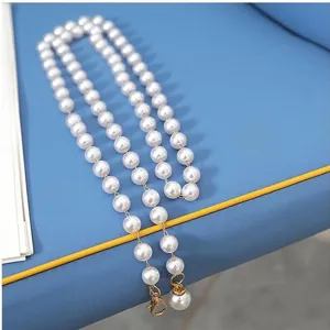 Detail view of a chic single-layer faux pearl waist chain dress accessory in white and gold.