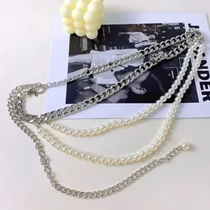 Detail view of the multi-layer body chain featuring metal curb links and classic faux pearls.