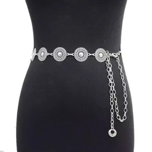 Detailed view of silver metal coin waist chain, vintage hollow flower body jewelry for women.