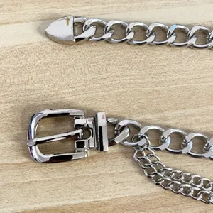 Close-up detail of punk style silver metal chain belt with classic buckle and tassel chains.