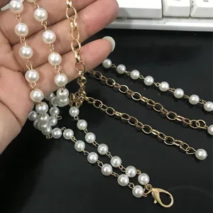 Vista detallada de la cadena de cintura de perlas multicapa con elegantes eslabones dorados.