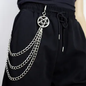 Detail view of punk style multi-layer metal pants chain with pentagram pendant on black trousers.