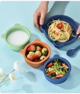 Détail bol ours en silicone présentant vaisselle bébé multicolore et disposition repas.