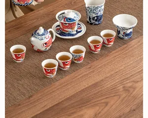 Traditional Chinese ceramic kung fu tea set detail with vibrant red carp pattern on wooden table.