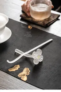 Frosted glass plum blossom tea needle and rest detail view, elegant tea ceremony desktop prop.