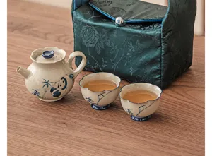 Ceramic tea set detail showcasing cute panda and bamboo design with portable green storage bag.