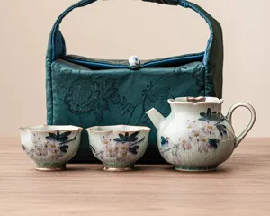 Juego de té de cerámica con magnolias pintadas a mano, una tetera, dos tazas y un estuche.