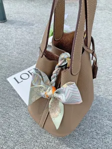 Detailed shot of leather bucket bag decorated with colorful printed silk scarf ribbon.