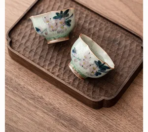 Taza de té de cerámica pintada a mano con esmalte craquelado y diseño de magnolia en detalle.
