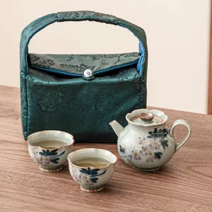 Juego de té de viaje de cerámica con una tetera dos tazas y bolsa con diseño de magnolia.
