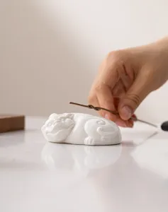 Dettaglio in primo piano del animale da tè Pixiu in ceramica bianca e portaoperchio.