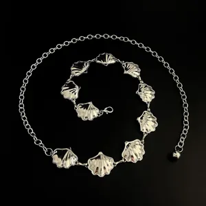Silver tone metal shell waist chain detail, featuring delicate seashell pendants and links.