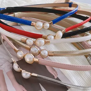 Vue détaillée d'une fine ceinture pour femme avec une élégante boucle de perles dorées.