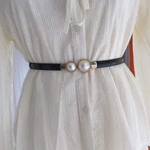 Vue détaillée d'une fine ceinture en cuir verni noir avec boucle en métal et perles élégantes.