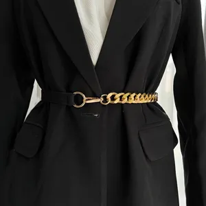 Détail de la ceinture femme élégante à chaîne dorée et élastique noir portée sur un blazer.