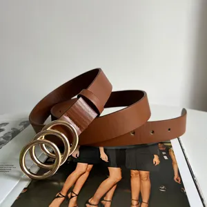 Brown leather belt featuring a chic triple gold-colored ring buckle, perfect for styling.