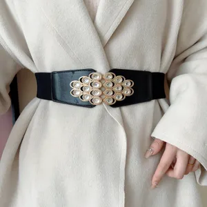 Detailed shot of black wide elastic waist belt with gold rhinestone metal buckle design.