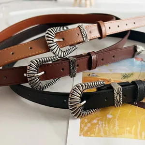 Close-up of retro western style leather belts with intricate metal buckles in multiple colors.