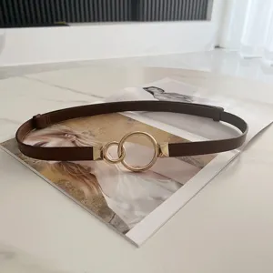 Detail view of adjustable brown thin waist belt with gold double ring buckle, perfect for dresses.