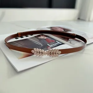 Elegant brown leather skinny belt featuring a stylish gold leaf metal buckle detail.