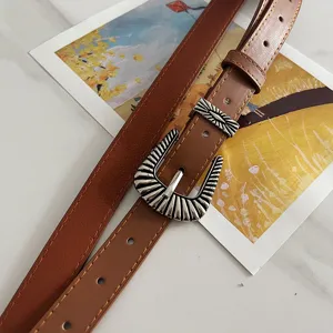 Detail view of American retro brown wide belt, featuring vintage silver carved metal buckle.