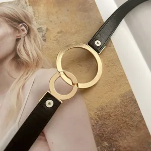 Black thin leather belt with gold circular metal rings, elegant waist chain for dress detail.