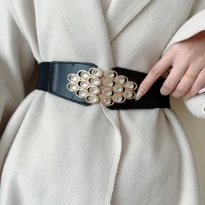Close up detail of women's black wide elastic waist belt with metal rhinestone buckle