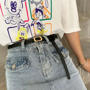 Close-up detail shot of a minimalist black thin belt paired with denim skirt, stylish and chic.