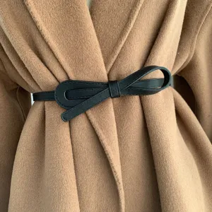 Gros plan détail d'une ceinture nœud en cuir synthétique noir sur un manteau.