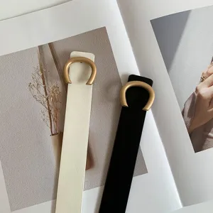 Gros plan détaillé de la ceinture fine pour femme avec boucle métallique en forme de C.