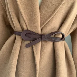 Gros-plan d'une ceinture nœud en similicuir marron foncé sur manteau pour robes et pulls.