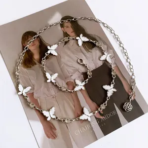 Detail shot of a minimalist silver chain belt featuring white butterfly charms and sparkling rhinestones.