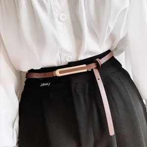Dettaglio di una sottile cintura in pelle marrone con elegante fibbia in metallo.